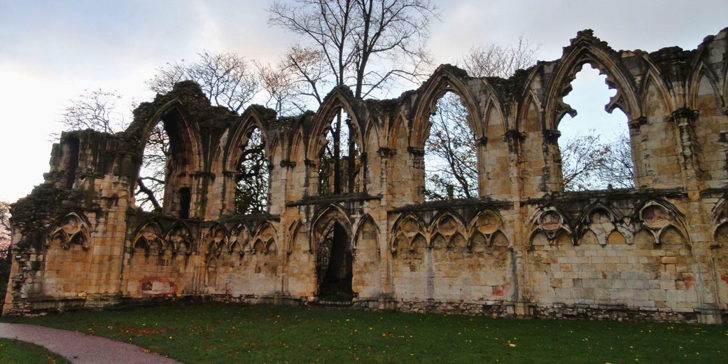 The ruins of a medieval Gothic structure with tall, pointed arches and intricate stone carvings.