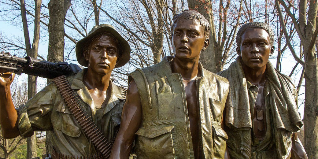 Three bronze statues of soldiers stand side by side in detailed uniforms, capturing a moment of unity and strength.
