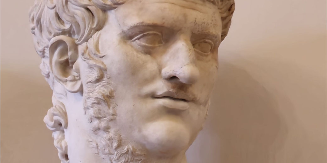 Marble bust of a man with curled hair, sideburns, and a faint mustache, gazing slightly to the side.