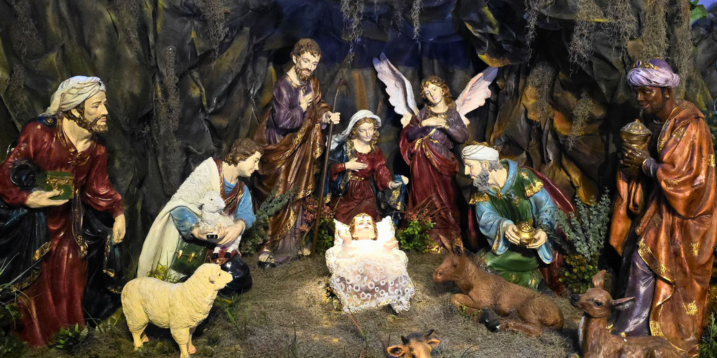 A nativity scene with figurines representing the birth of Jesus, including Mary, Joseph, angels, shepherds, wise men, and animals, centered around baby Jesus in a manger.