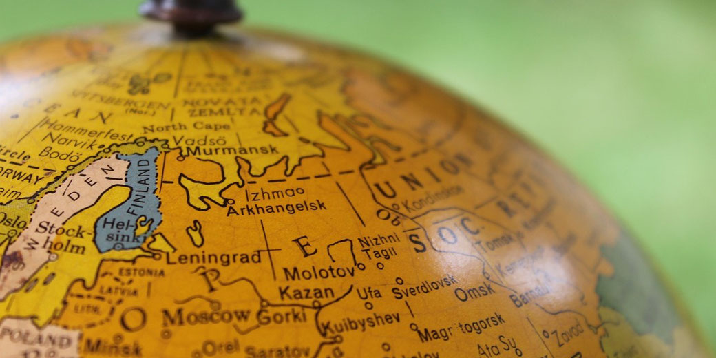 Close-up of a vintage globe focused on northern Europe and western USSR, showing place names like Leningrad, Moscow, and Helsinki.
