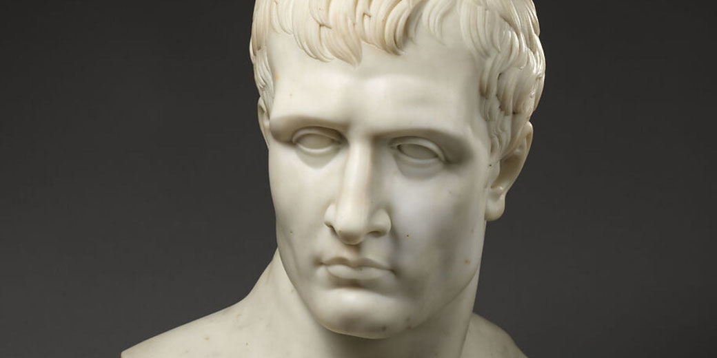 A marble bust depicting Napoleon with idealized classical features, based on Canova’s sculpture. The figure is shown with a smooth surface and a composed expression.