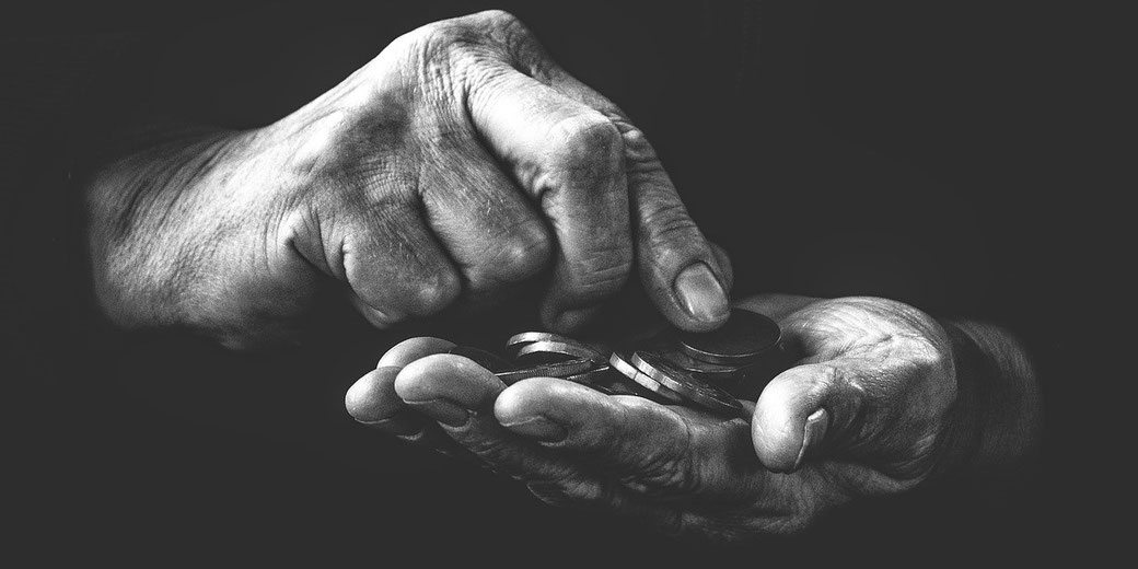 A pair of aged hands holds and counts a small stack of coins in a high-contrast black-and-white image.