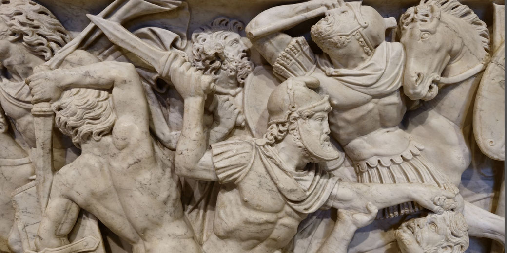 Detailed marble relief of chaotic battle with Roman soldiers fighting, wielding swords and shields among fallen and struggling enemies.