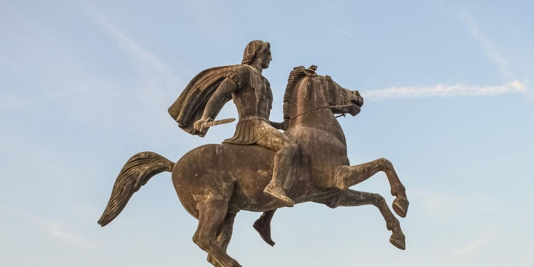 A bronze equestrian statue of a warrior, possibly Alexander the Great, holding a sword while riding a rearing horse. His flowing cape and determined gaze add to the dynamic composition.