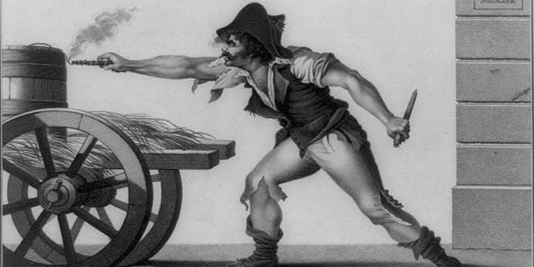 A man in tattered clothes lights a fuse on a cart's barrel while gripping a knife, appearing ready for sabotage or attack.