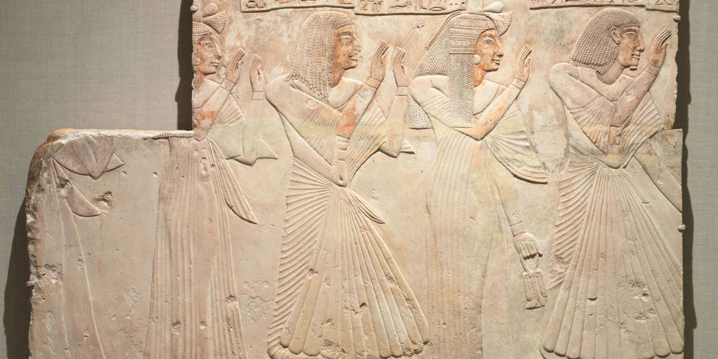 Painted limestone relief showing Amenhotep and family in prayer, adorned in pleated garments and wigs, from his tomb chapel at Asyut.