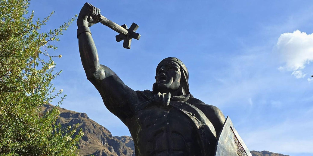 n Inca warrior in a dramatic pose, holding a cross-shaped weapon aloft and carrying a shield.