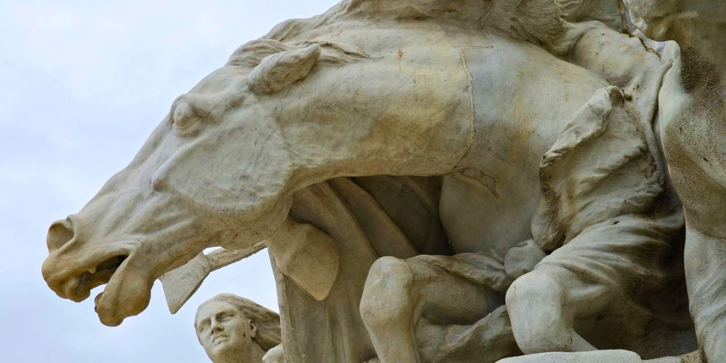 Detailed marble sculpture of a rearing horse with flared nostrils and open mouth, alongside dynamic human figures beneath it, full of motion and intensity.