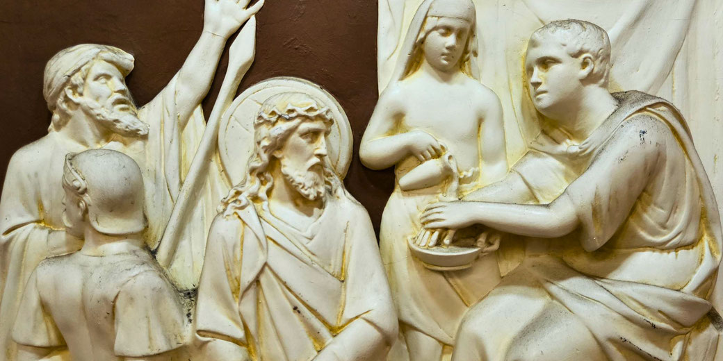 A relief sculpture of Pontius Pilate washing his hands, symbolizing his denial of responsibility for Jesus' fate, surrounded by other figures, including Jesus with a crown of thorns.