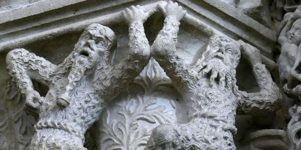 Stone relief of two bearded figures lifting arms, detailed carving on architectural panel with textured surface and aged appearance.