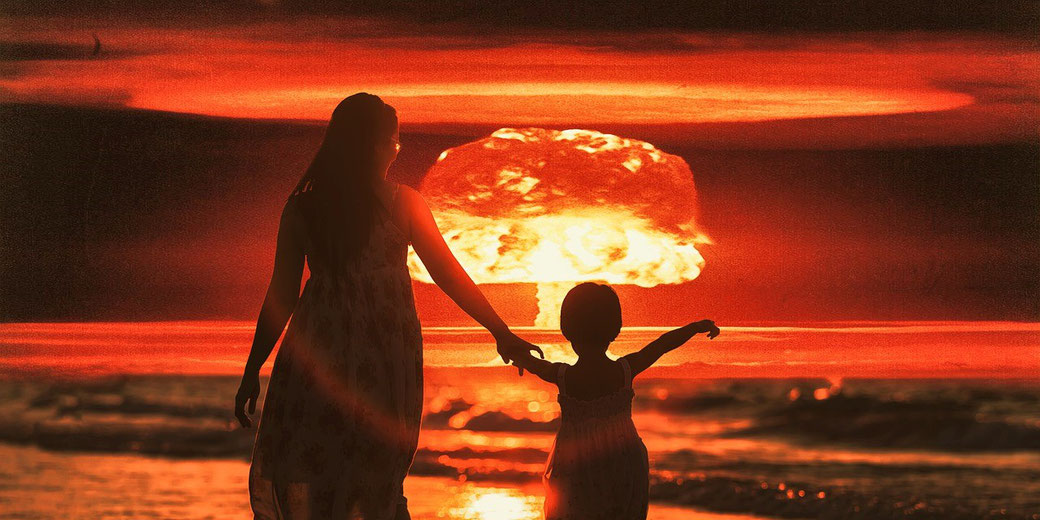 A woman and child hold hands on a beach while a massive explosion lights up the sky in the distance.