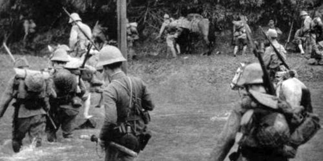 Soldiers in full gear cross a river during a military operation, with rifles and supplies visible; horses and more troops gather on the opposite bank.