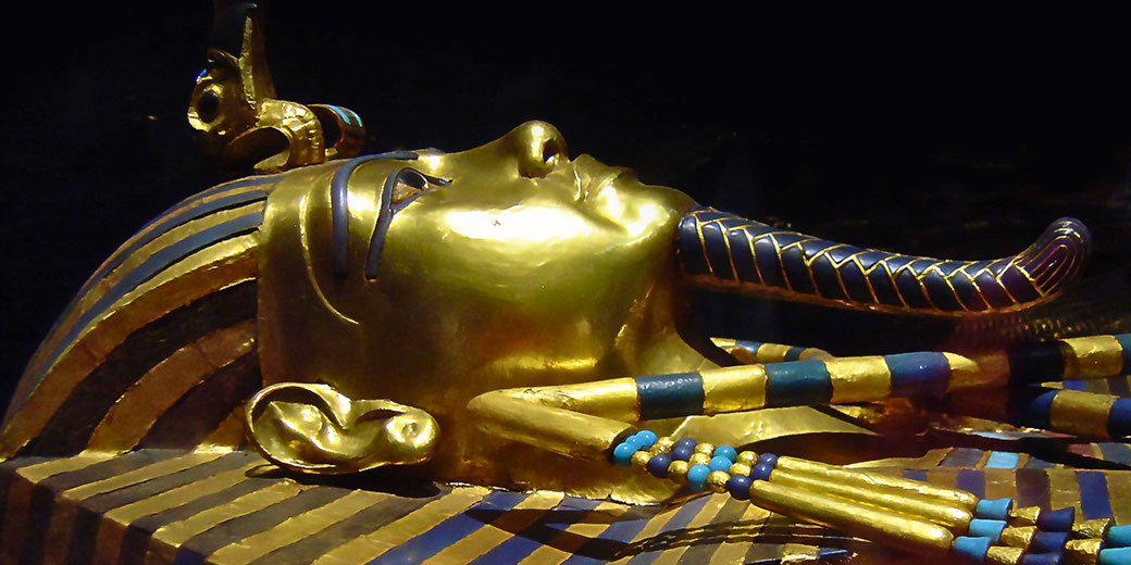 The iconic golden funerary mask of Tutankhamun, adorned with blue and gold stripes and intricate details, symbolizing the opulence and artistry of ancient Egyptian burial traditions.