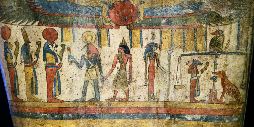 Ancient Egyptian artwork depicting gods and a judgment scene with symbolic figures and a scale, featuring vibrant red, blue, and yellow tones.