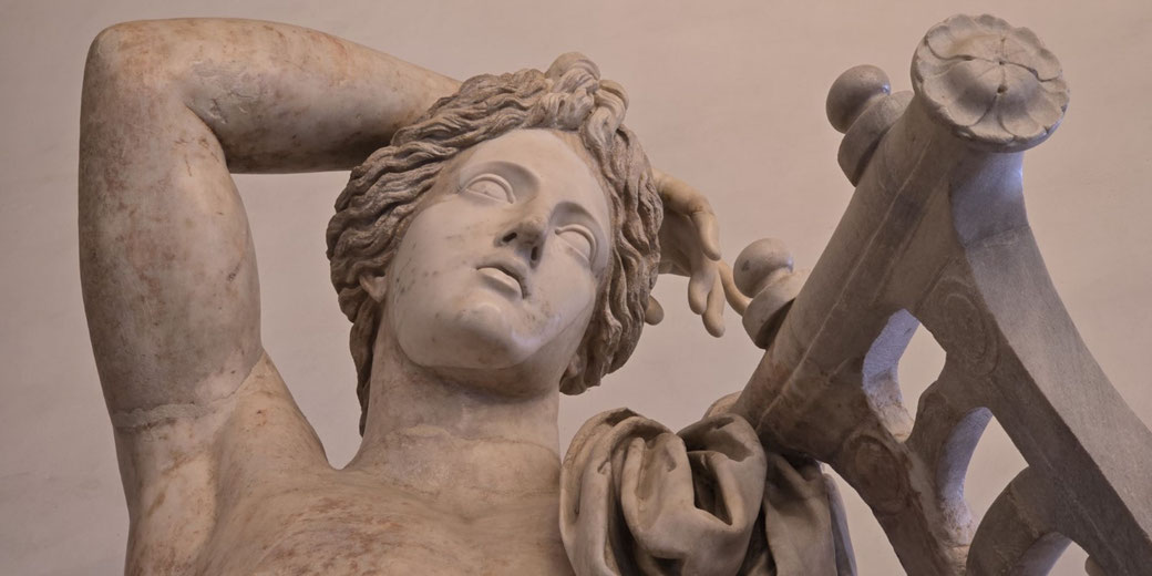 Close-up of a marble statue's serene face, head tilted back, hand resting behind, leaning on a detailed lyre.