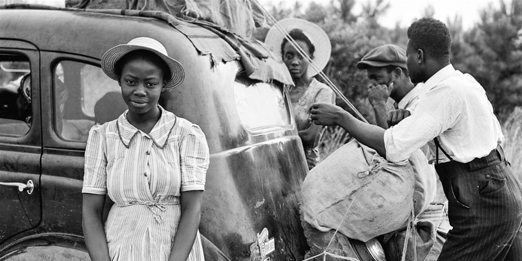 African American woman leaning against a car