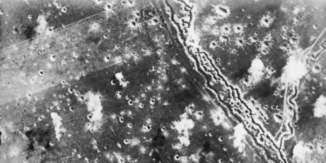 Aerial view of a World War I battlefield shows zigzag trenches and land scarred with countless shell craters.