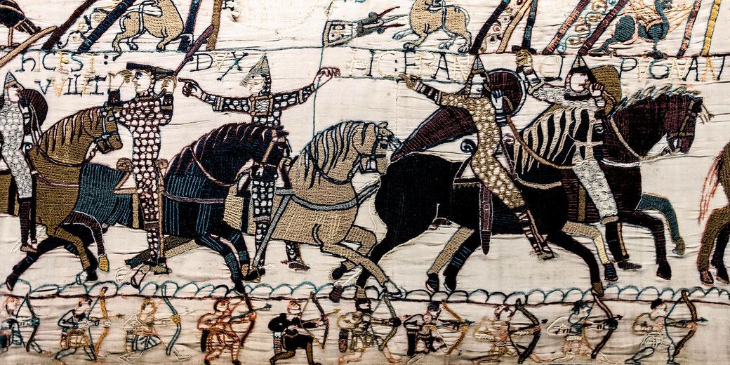 Section of the Bayeux Tapestry showing embroidered knights on horseback in battle with archers below.