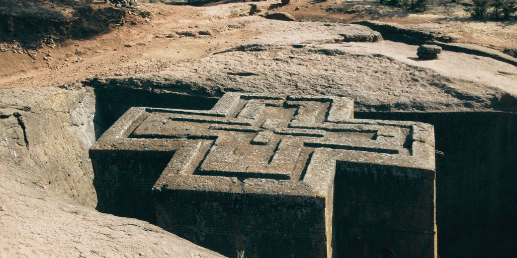Rock-hewn church in the shape of a cross carved directly into the ground in Lalibela, Ethiopia.