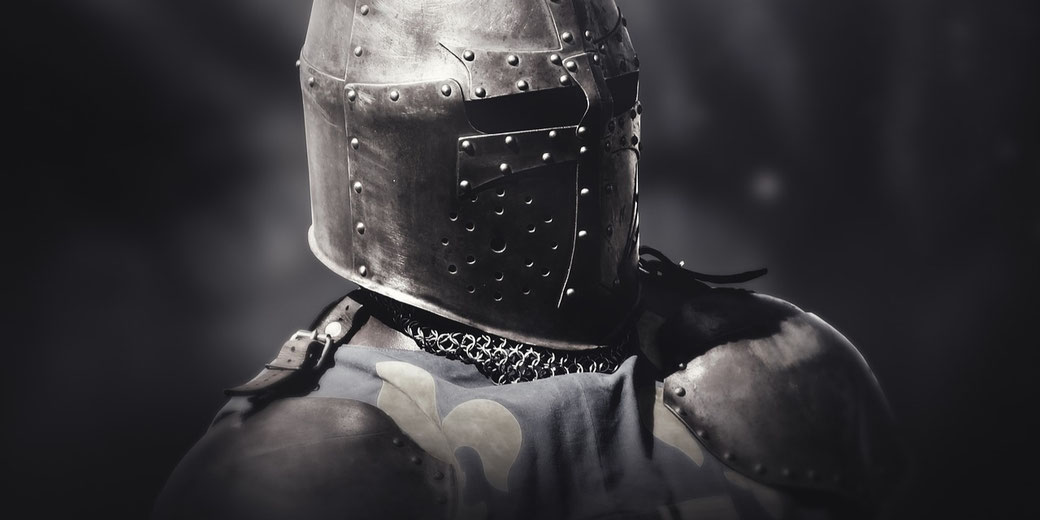 Close-up of a medieval knight in full armor and a steel helmet with a dark, blurred background.