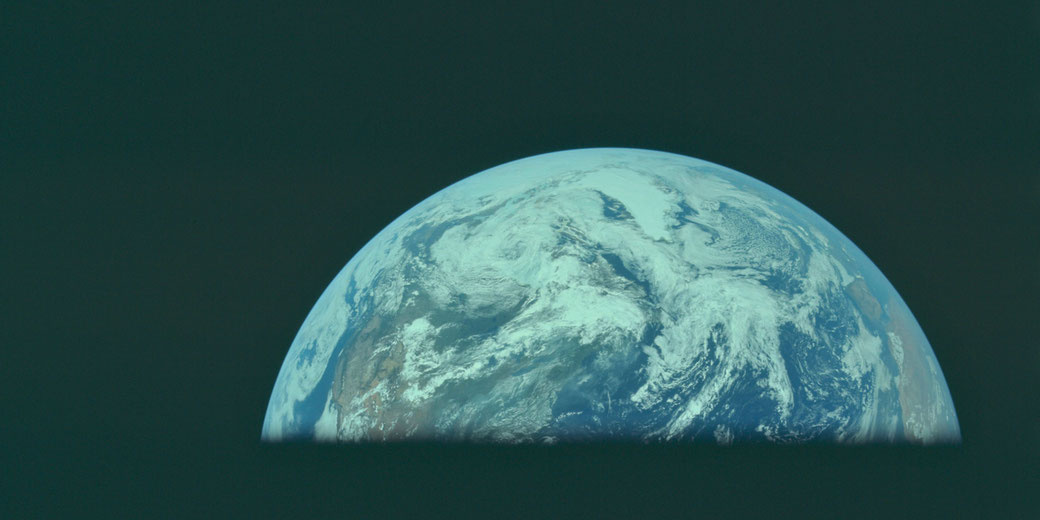 Half of Earth is visible rising above a dark foreground, with swirling clouds and continents in view against the blackness of space.