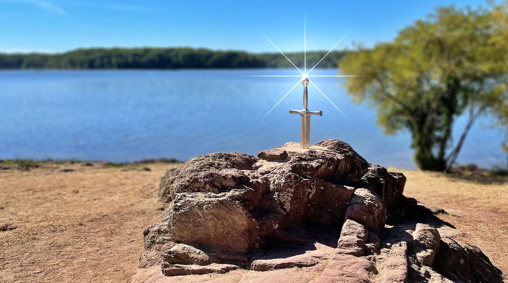 A shining sword embedded in a rock near a lake, evoking the legend of Excalibur.