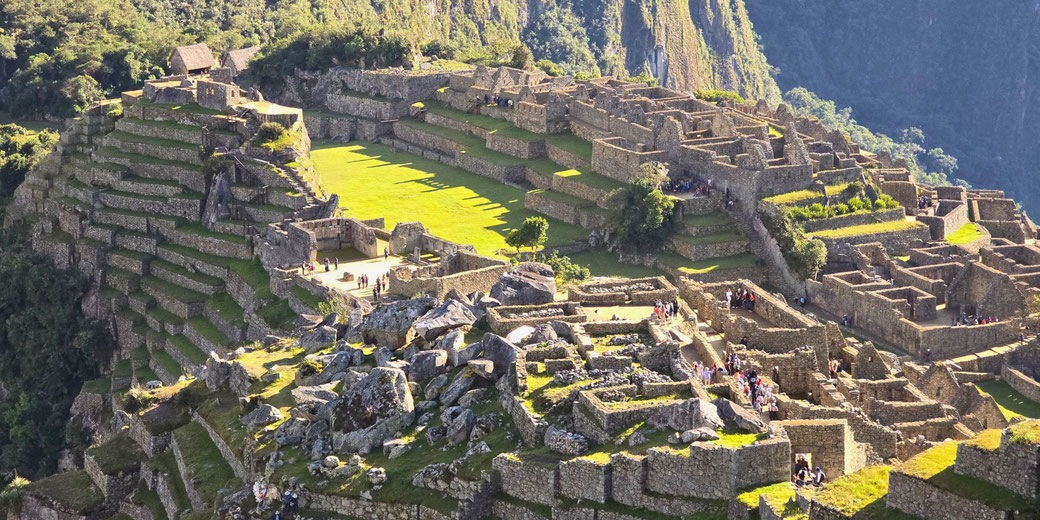 A breathtaking view of Machu Picchu, the ancient Incan citadel in the Andes Mountains of Peru, featuring terraced fields, stone ruins, and visitors exploring the historic site.