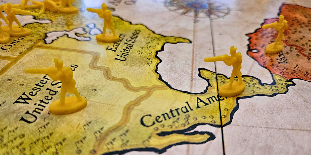 Yellow toy soldiers are placed on a board game map showing parts of North and Central America.