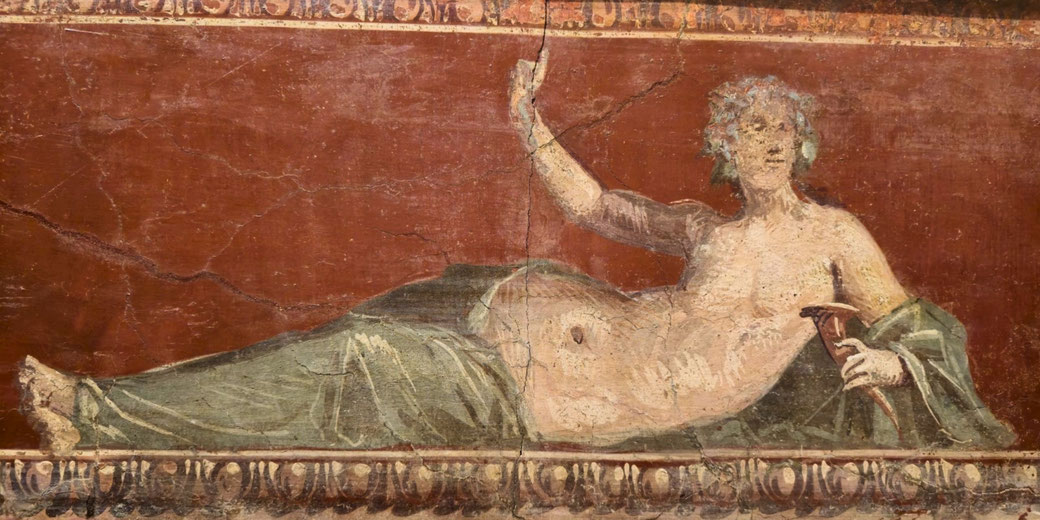 Ancient fresco of a reclining figure with a green drape, holding a horn-shaped object, set against a deep red background with decorative border.