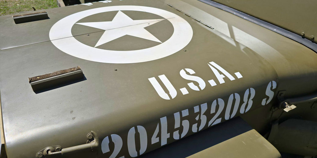 Close-up of an olive drab U.S. military vehicle hood showing a white star emblem and stenciled serial numbers.