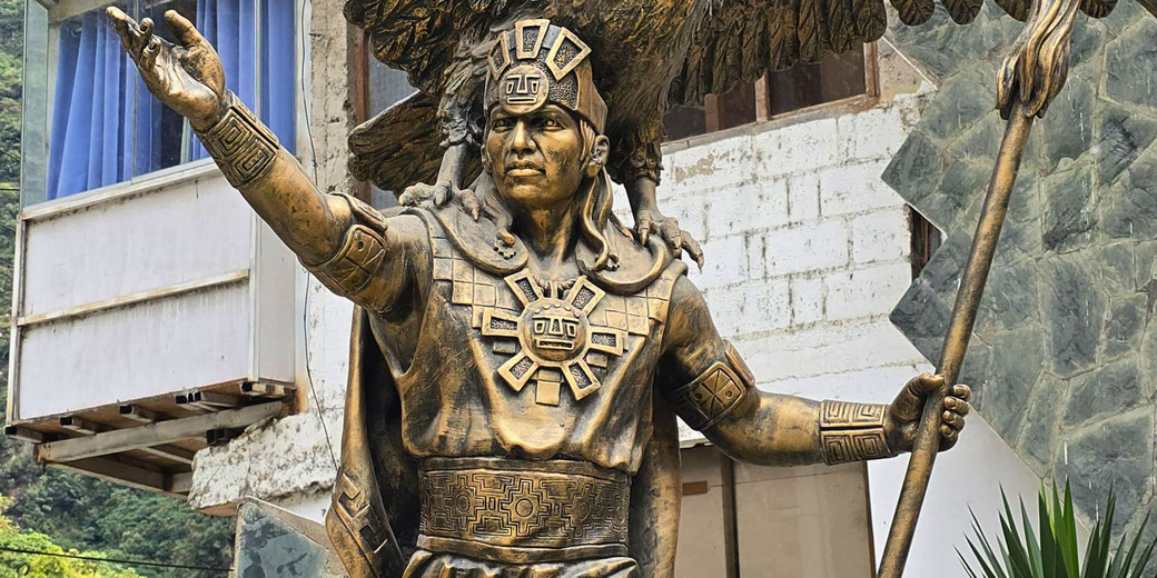 A golden statue of an Inca ruler, possibly Pachacuti, wearing traditional attire with intricate patterns. He holds a staff and extends a hand, while a large bird, likely a condor, spreads its wings behind him.