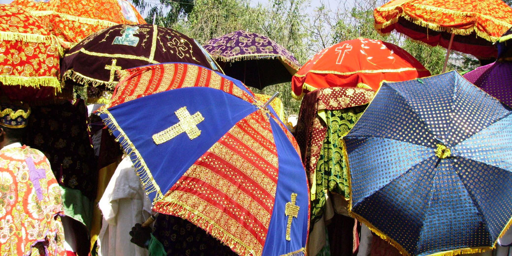 A procession with vibrant, embroidered umbrellas used in Ethiopian Orthodox Christian ceremonies. These ornate parasols symbolize reverence and are carried by clergy during religious events.