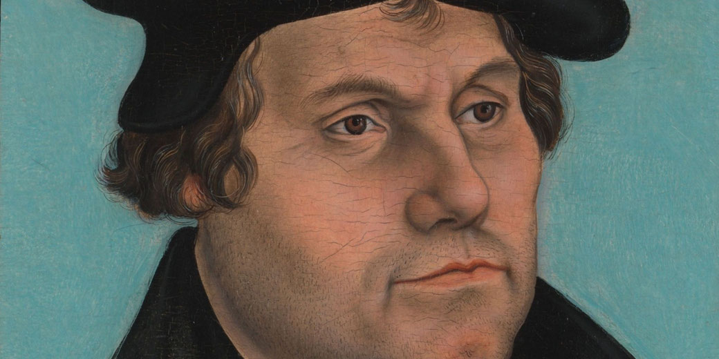 A detailed portrait of Martin Luther, the 16th-century Protestant reformer. He has short, wavy hair and a serious expression, wearing a black cap and a dark robe against a light blue background.