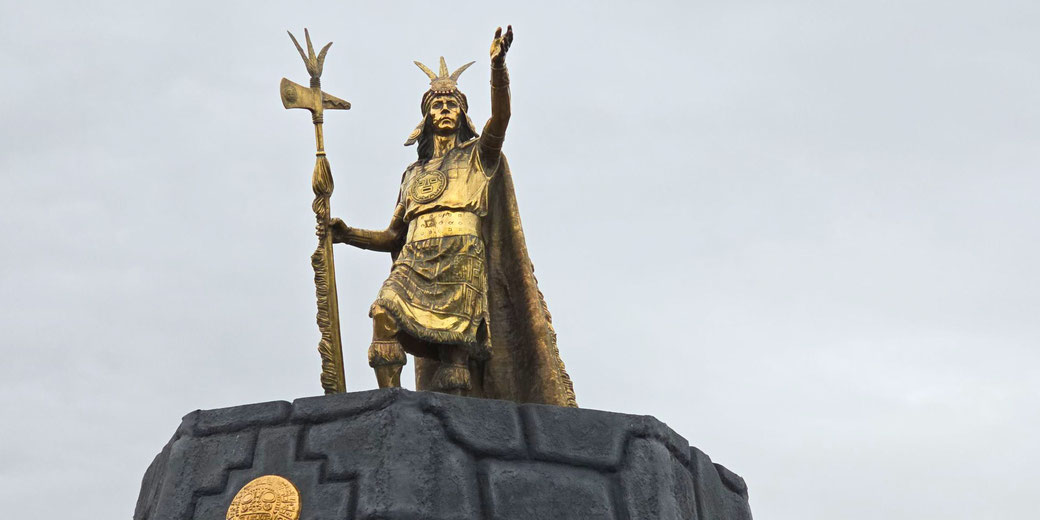 A bronze statue of Pachacuti, the Inca ruler who expanded the empire. He stands atop a stone pedestal, holding a ceremonial staff, symbolizing his leadership and legacy.