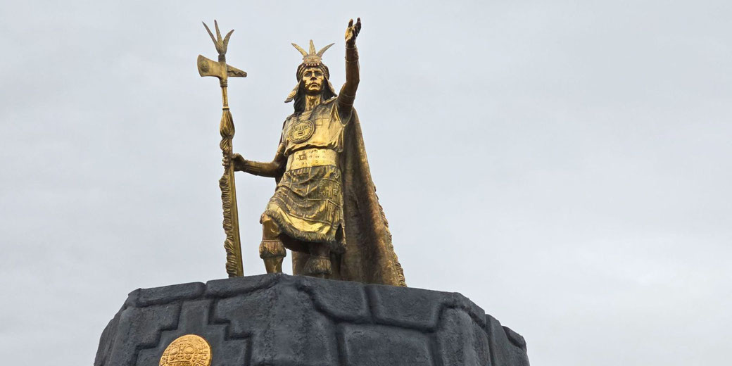 A bronze statue of Pachacuti, the Inca ruler who expanded the empire. He stands atop a stone pedestal, holding a ceremonial staff, symbolizing his leadership and legacy.