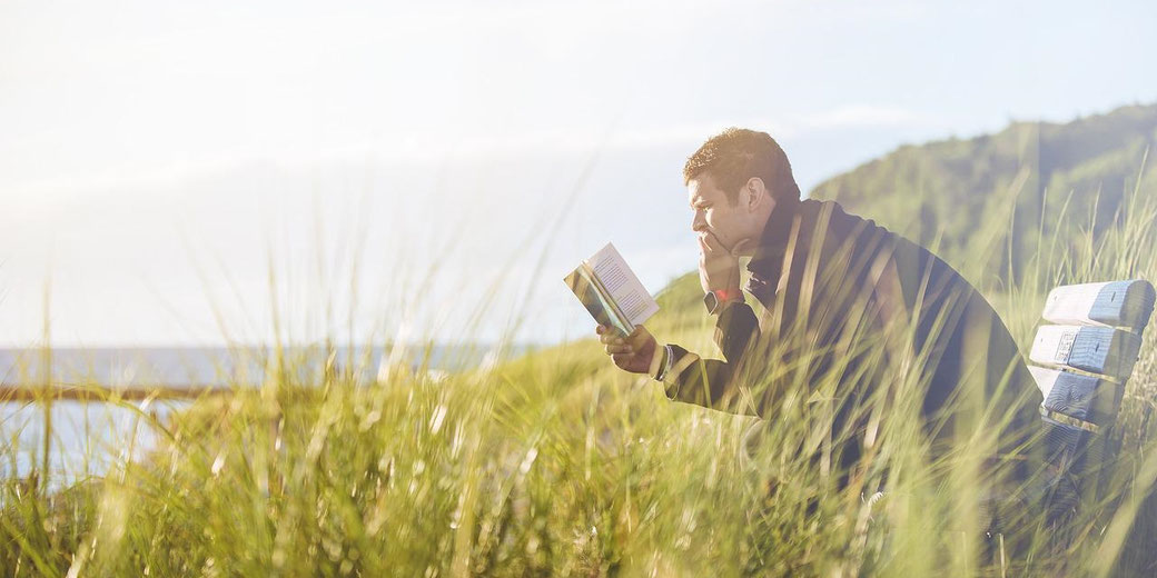 Man reading a book in a field