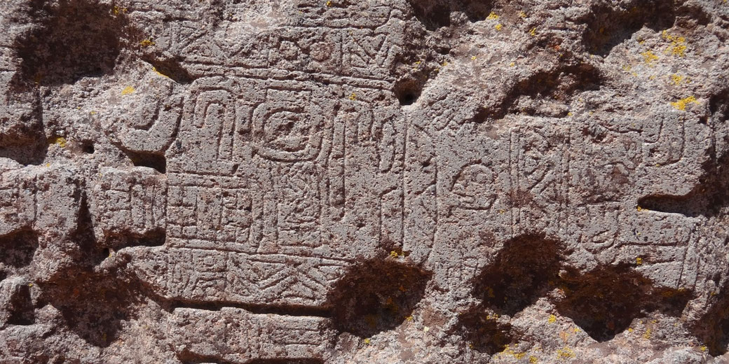 An ancient rock carving with intricate symbols and figures, possibly from a pre-Columbian civilization in South America.