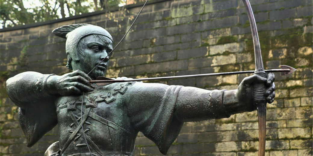 A statue of Robin Hood, depicted aiming a bow with a focused expression, capturing his legendary role as an outlaw archer in medieval English folklore.