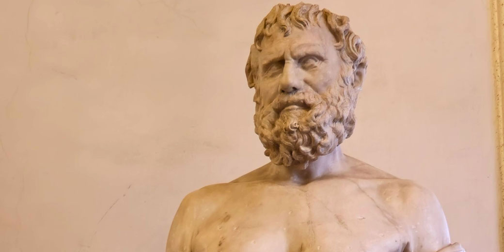 Marble bust of a Roman man with short hair and draped robes, gazing slightly upward with a composed expression.
