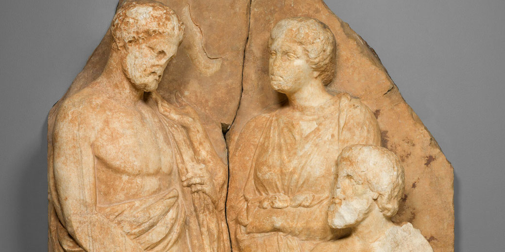 Marble relief showing three figures; two men clasp hands in farewell, observed by a seated woman, likely family members.