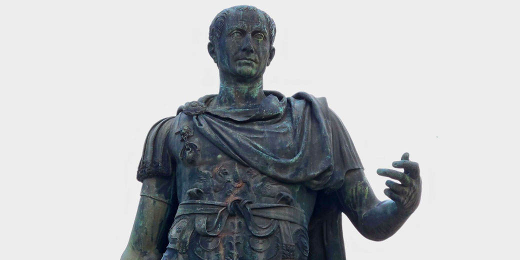 Bronze statue of a Roman leader in military attire, wearing a cloak and armor, with one arm extended in a commanding gesture.