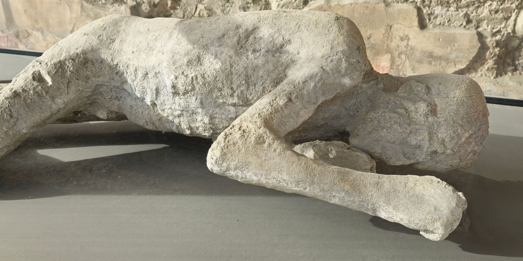 A plaster cast of a person lying face down, preserving their final moments during the eruption of Mount Vesuvius in Pompeii.