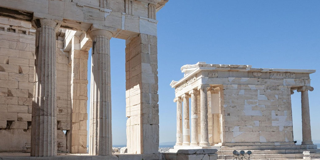 Ancient Greek temple columns and marble structures under a clear blue sky at the Acropolis in Athens.
