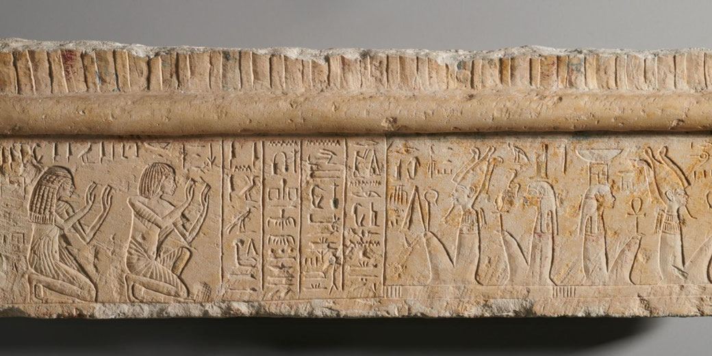 Limestone lintel fragment showing Iniuia and Iuy kneeling with raised hands in worship before the deities Osiris and Isis, carved and painted during the reign of Tutankhamun.