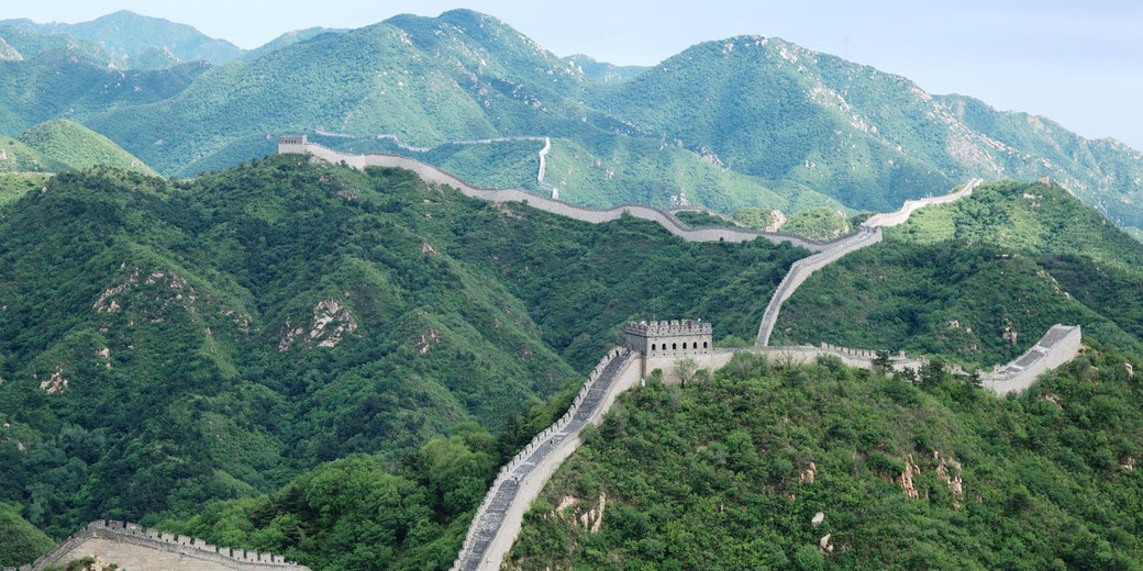he Great Wall of China stretching over green mountains, with watchtowers along its winding path.