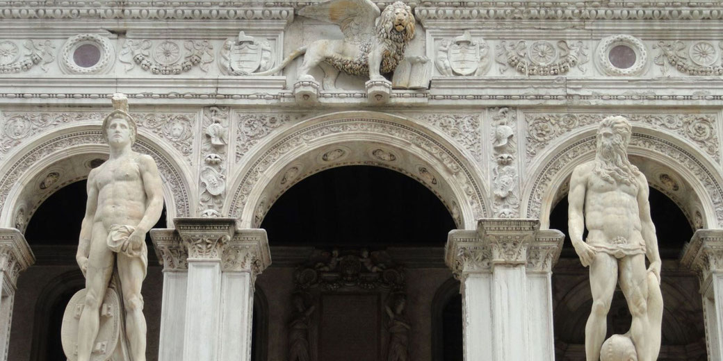 The façade of the Doge’s Palace in Venice, featuring statues of Mars and Neptune, along with the iconic winged Lion of St. Mark, symbolizing the power of the Venetian Republic.