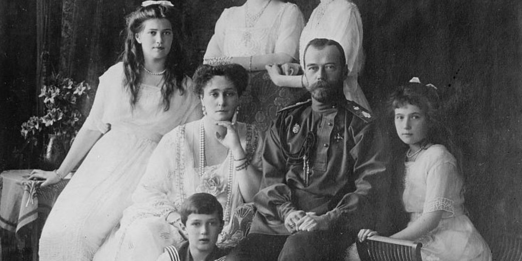 Black and white portrait of a royal family with parents and five children dressed in formal attire, seated and standing indoors.