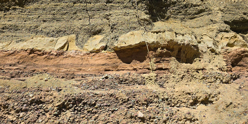 Layered sedimentary rock with visible bands of different textures and colors, indicating geological stratification and erosion over time.
