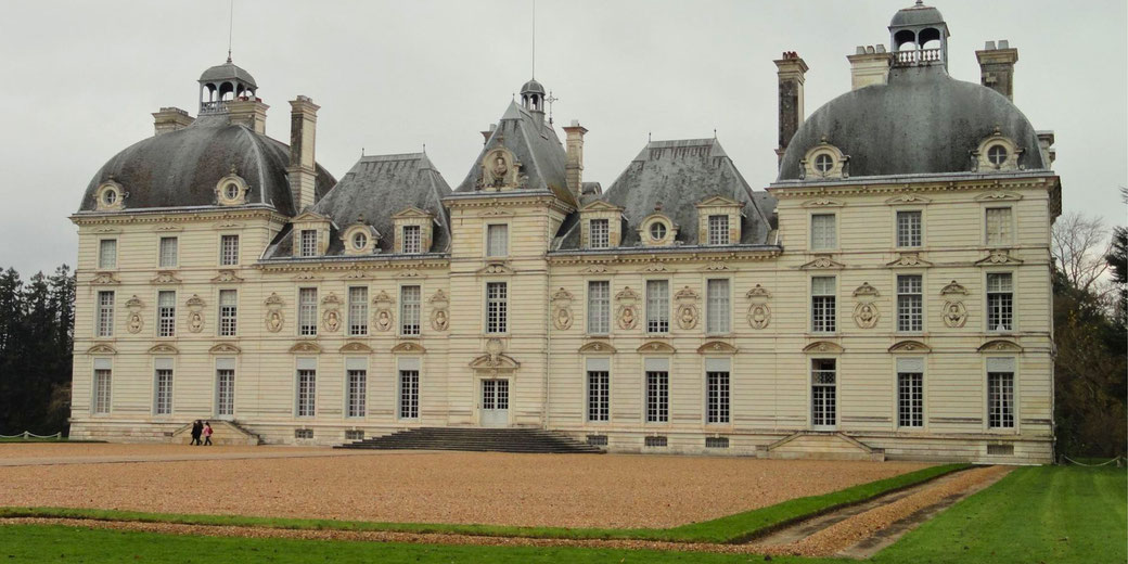 Château de Cheverny, a grand 17th-century French château with symmetrical architecture, elegant domed towers, and intricate detailing, set against a gravel courtyard and green lawns.